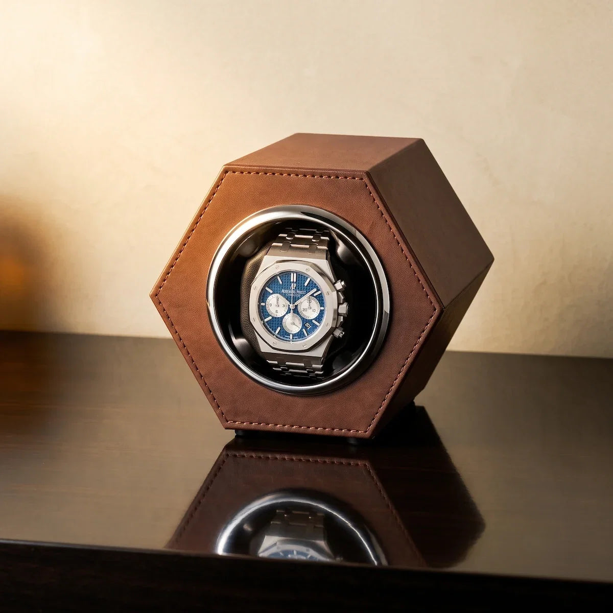 Remontoir de montre hexagonal en cuir végan marron avec une montre automatique sur une table sombre.
