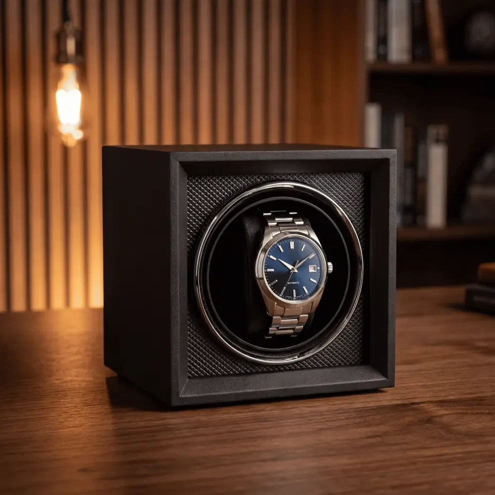 Remontoir de montre cube noir en bois et flanelle avec une montre automatique à cadran bleu sur un bureau en bois.
